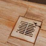 Dirty and clogged shower drain with rust stains and hair, illustrating common plumbing issues related to drain clogs.