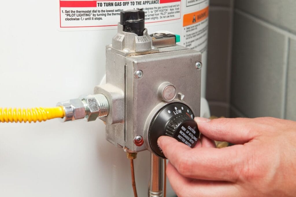 7 Signs It’s Time to Replace Your Water Heater 2 Close-up of a person adjusting the temperature knob on a water heater, contemplating when to replace the unit for optimal efficiency.
