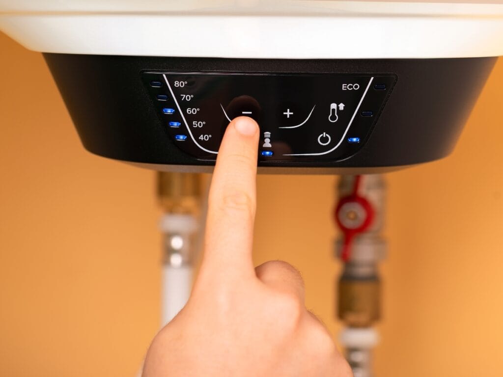 Benefits of Tankless Water Heaters for Energy-Efficient Homes 7 A person presses a button on an electric water heater control panel to adjust the temperature setting, showcasing the benefits of tankless water heaters for energy-efficient homes.